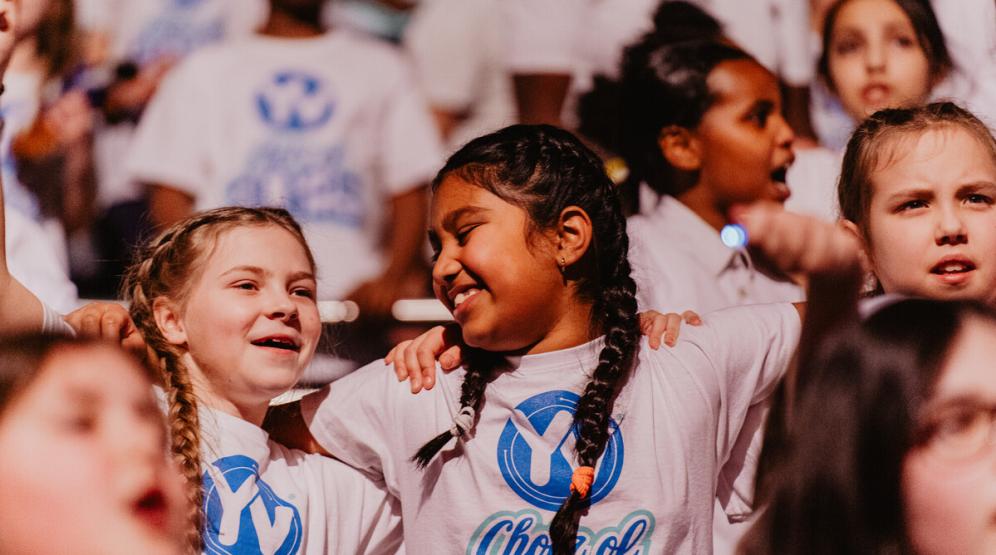 A group of children smile and sing.