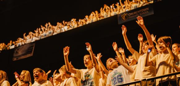 A group of children smile while singing.